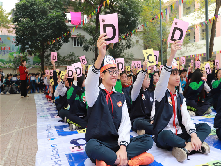 A group of people sitting on the ground holding up signsDescription automatically generated