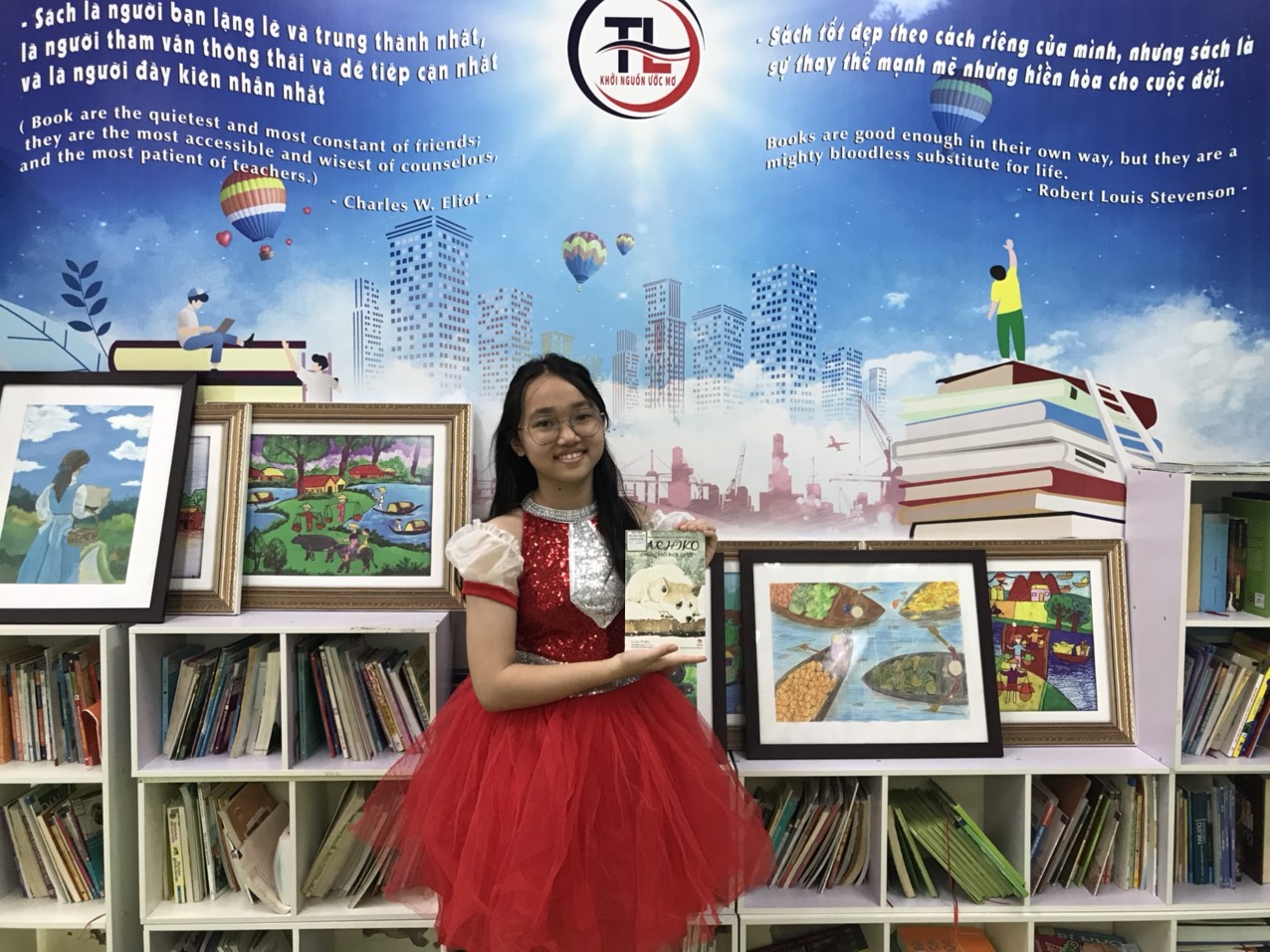 A child in a red dress holding a bookDescription automatically generated
